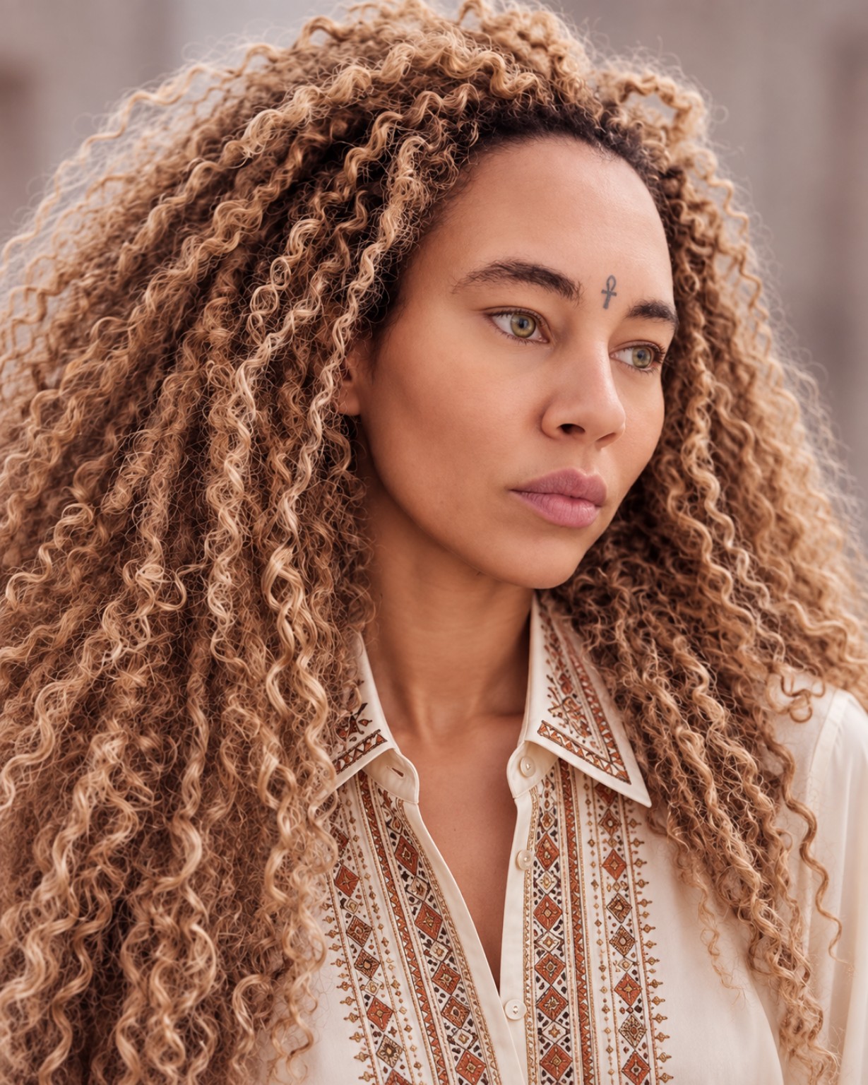Portrait d’Eva Durand aux cheveux bouclés, vêtue d’une chemise écrue brodée.